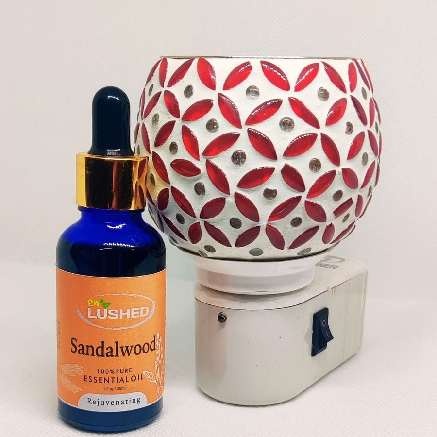 Sandalwood essential oil dropper bottle by enlushed beside a decorative ceramic oil burner