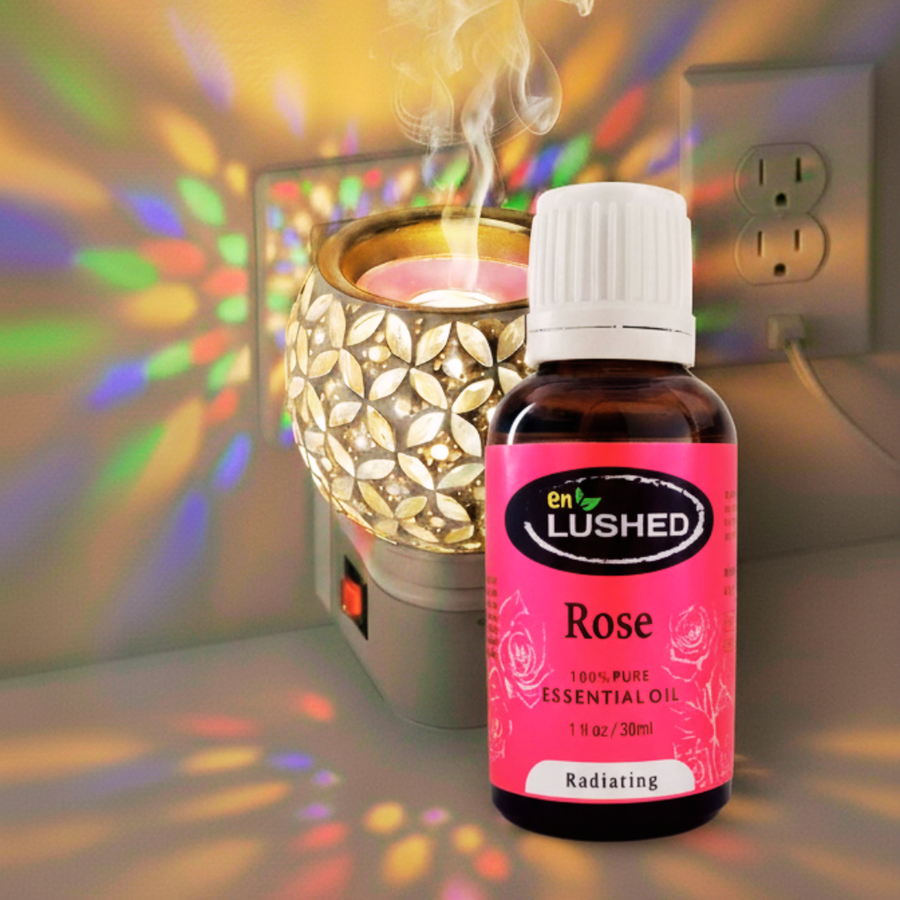 Rose essential oil dropper bottle by enlushed beside a glowing ceramic oil diffuser
